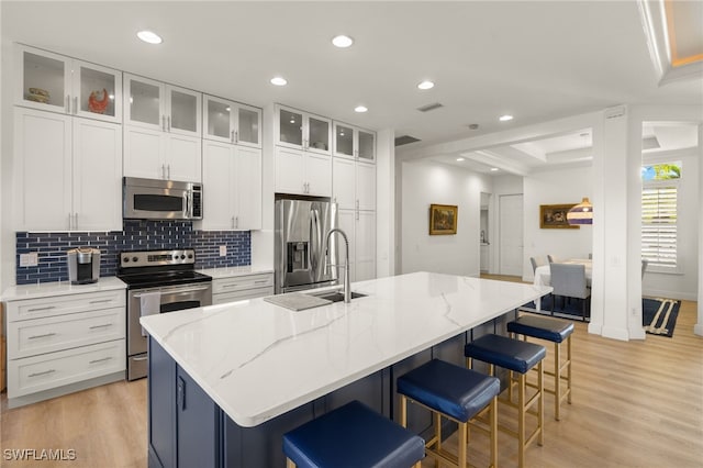kitchen with light wood-style flooring, white cabinetry, appliances with stainless steel finishes, and tasteful backsplash