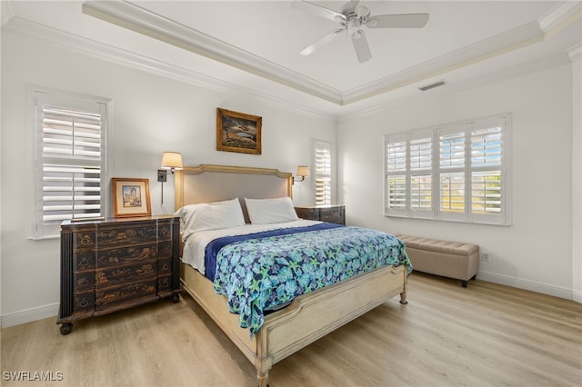 bedroom with ornamental molding, wood finished floors, a tray ceiling, and visible vents