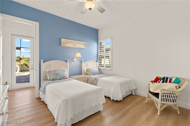 bedroom with baseboards, wood finished floors, access to exterior, and multiple windows
