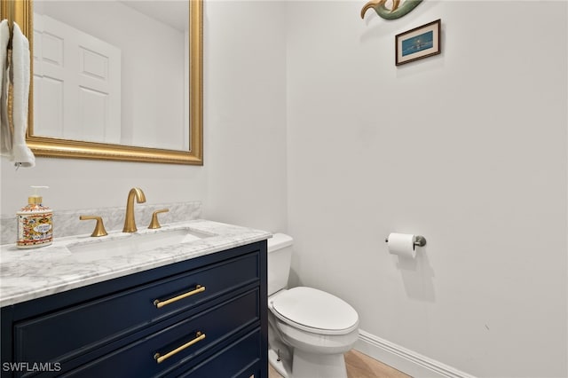 bathroom featuring baseboards, vanity, and toilet
