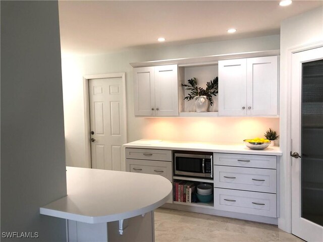 411 SW 34th Ter, Cape Coral, FL 33914 - kitchen with stainless steel microwave, light countertops, open shelves, white cabinets, and recessed lighting