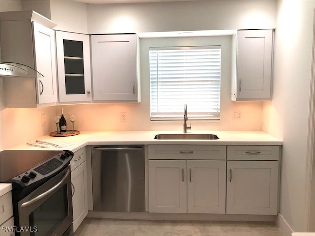 411 SW 34th Ter, Cape Coral, FL 33914 - kitchen featuring stainless steel appliances, a sink, wall chimney range hood, light countertops, and glass insert cabinets