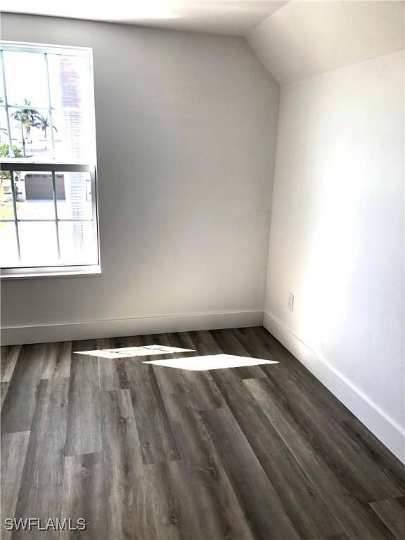 411 SW 34th Ter, Cape Coral, FL 33914 - spare room featuring wood finished floors, baseboards, and vaulted ceiling