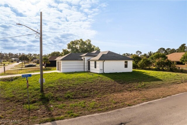 5327 Beauty St, Lehigh Acres, FL 33971 - view of side of home featuring a lawn and stucco siding