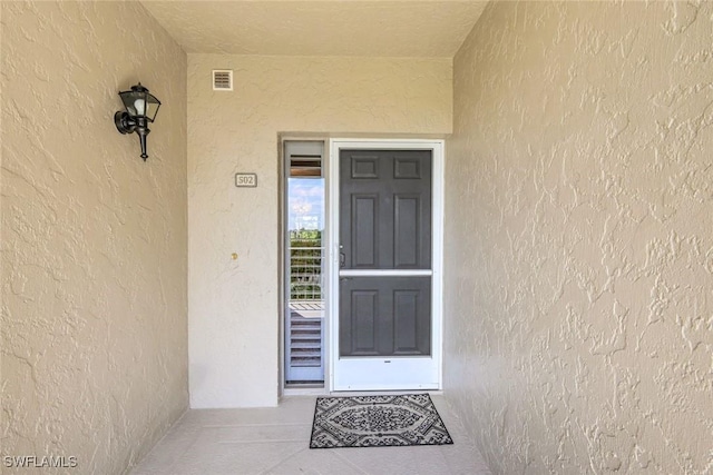 entrance to property with stucco siding and visible vents