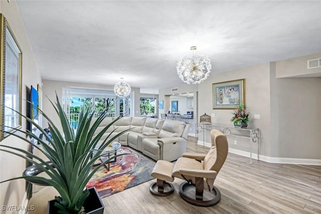 living area with visible vents, baseboards, a notable chandelier, and wood finished floors