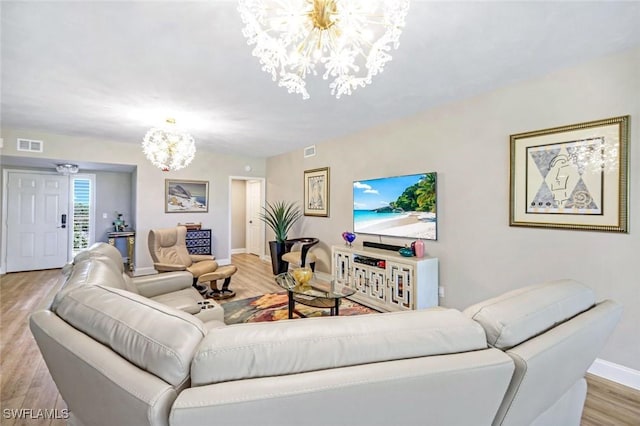 living area with visible vents, baseboards, an inviting chandelier, and wood finished floors