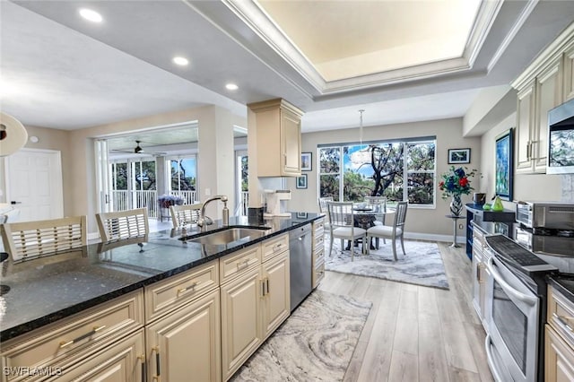 kitchen with baseboards, light wood-style flooring, cream cabinets, appliances with stainless steel finishes, and a sink