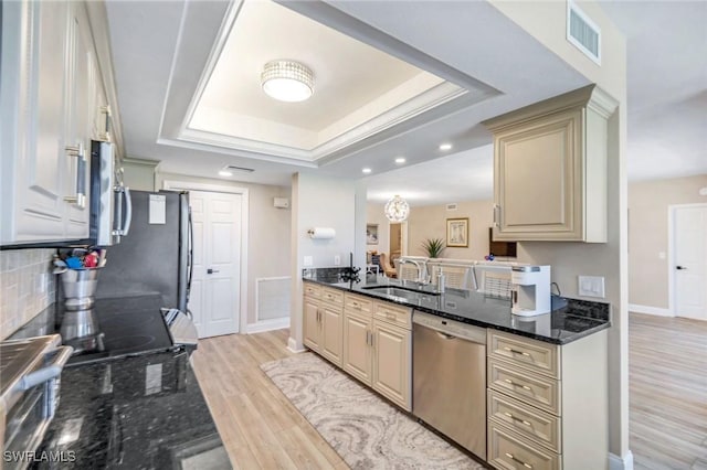 kitchen featuring light wood-style flooring, visible vents, a sink, stainless steel appliances, and a raised ceiling