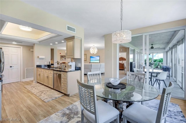 dining area featuring light wood-type flooring, visible vents, a raised ceiling, baseboards, and a notable chandelier