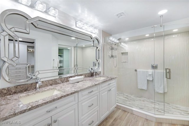 bathroom featuring a shower stall, wood finished floors, a sink, and visible vents