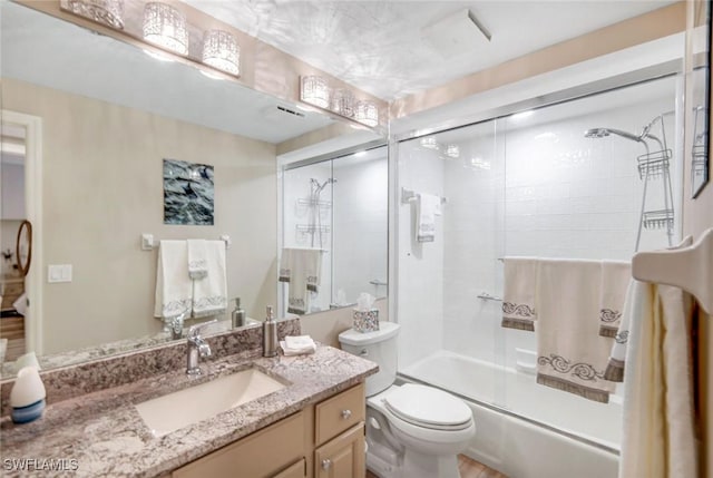 bathroom featuring combined bath / shower with glass door, vanity, and toilet