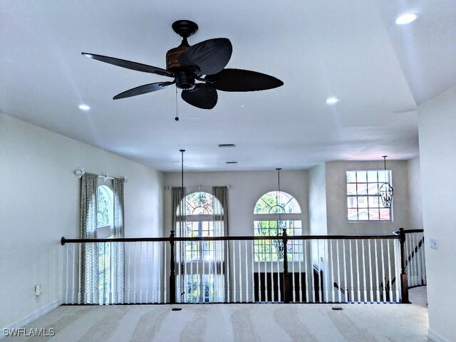 spare room with ceiling fan with notable chandelier, baseboards, plenty of natural light, and carpet floors