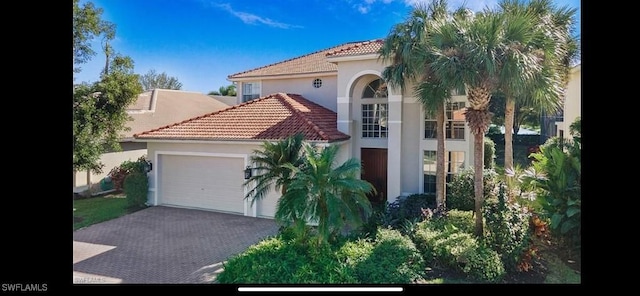 mediterranean / spanish-style home with driveway, stucco siding, an attached garage, and a tile roof
