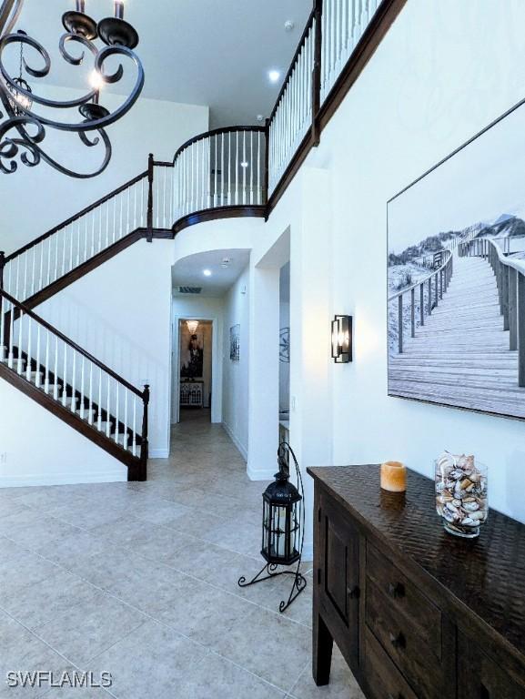 foyer with baseboards, a notable chandelier, a towering ceiling, stairs, and tile patterned floors