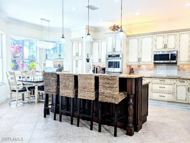 kitchen with tasteful backsplash, ornamental molding, appliances with stainless steel finishes, and a kitchen bar