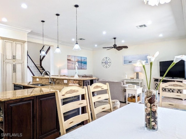 kitchen with open floor plan, crown molding, a sink, and visible vents