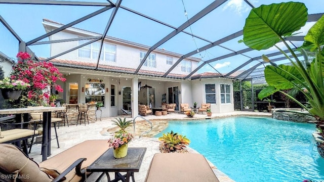 view of pool with outdoor dry bar, a patio area, a pool with connected hot tub, and glass enclosure