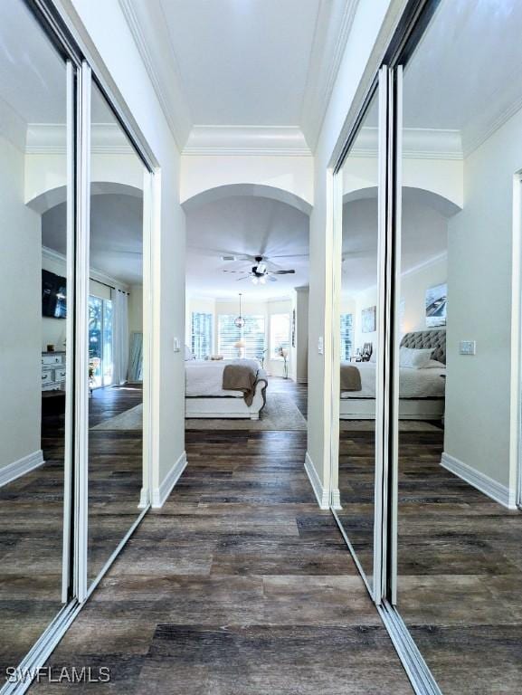hallway with dark wood-type flooring, arched walkways, and baseboards