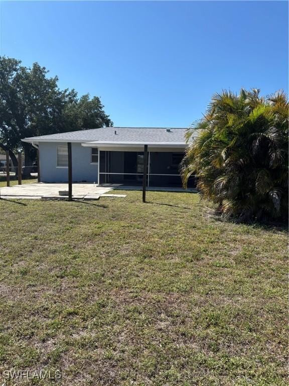 rear view of house featuring a lawn and a sunroom