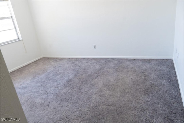 empty room featuring baseboards and carpet flooring