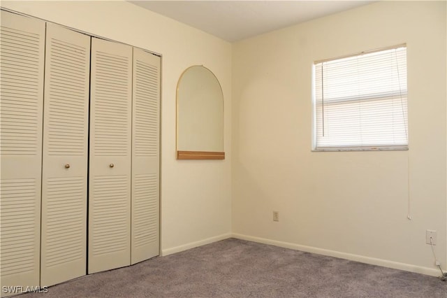 unfurnished bedroom with a closet, baseboards, and carpet flooring