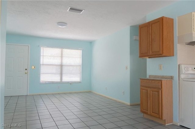 kitchen featuring visible vents, baseboards, washer / clothes dryer, light countertops, and light tile patterned floors