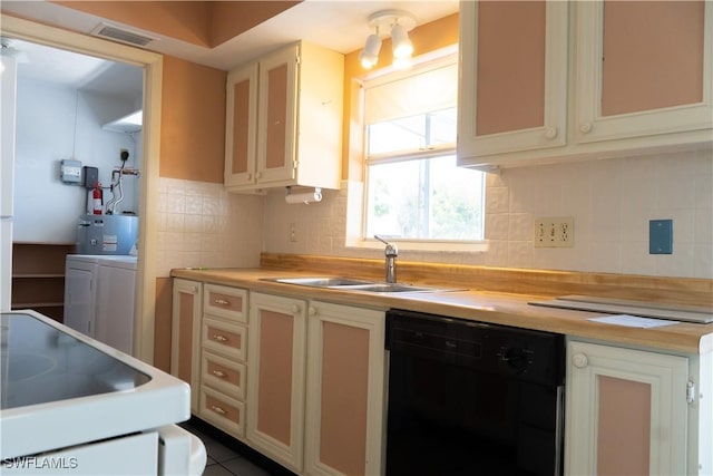 kitchen with a sink, black dishwasher, backsplash, visible vents, and washing machine and dryer