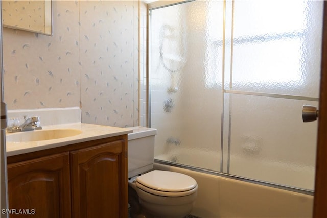 bathroom featuring vanity, combined bath / shower with glass door, and toilet