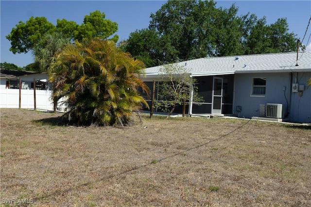 rear view of house with a lawn, fence, central AC unit, and a sunroom