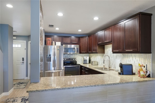 1315 SW 47th Ter Unit 102, Cape Coral, FL 33914 - kitchen featuring appliances with stainless steel finishes, a sink, light stone counters, dark brown cabinetry, and light wood-style flooring