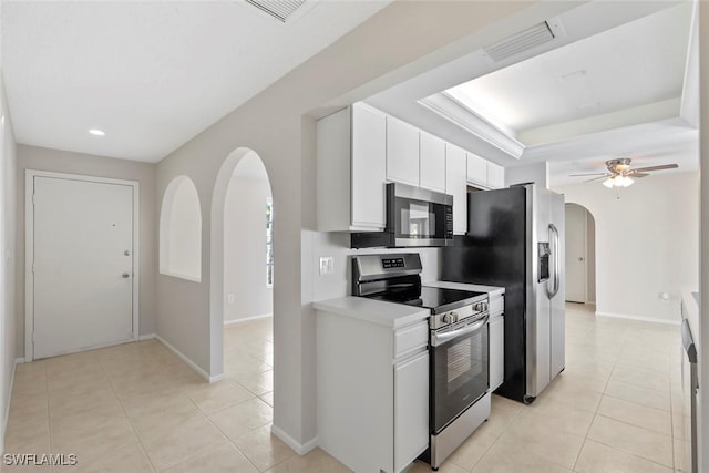 6874 Carmelle Dr, Fort Myers, FL 33919 - kitchen featuring stainless steel appliances, arched walkways, light tile patterned floors, white cabinets, and baseboards