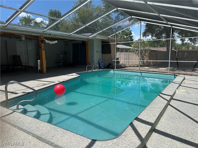 view of pool with fence, a fenced in pool, a patio area, and glass enclosure
