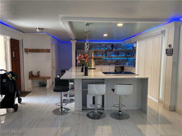 bar with black electric stovetop and marble finish floor