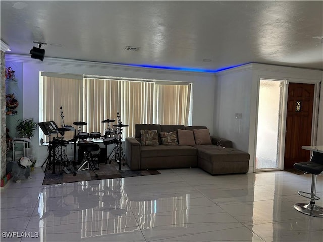 living area with visible vents and crown molding