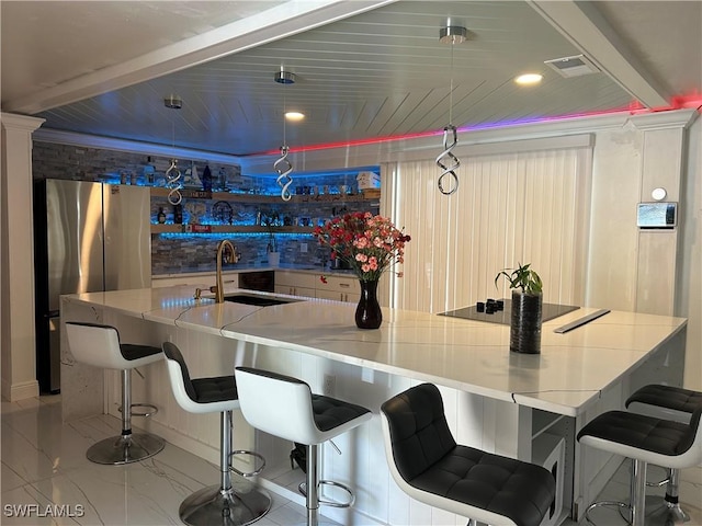 bar with visible vents, black electric cooktop, a sink, baseboards, and freestanding refrigerator