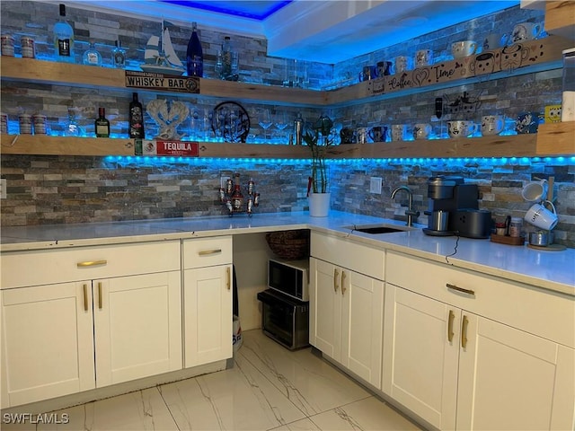 bar with backsplash, wet bar, a sink, and marble finish floor
