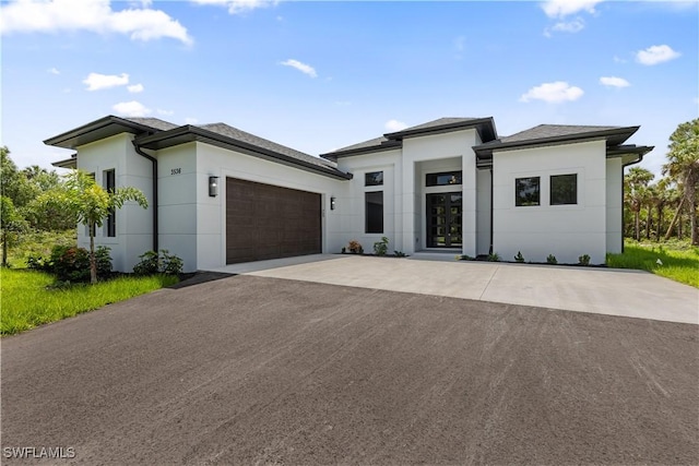 prairie-style house featuring stucco siding, an attached garage, and driveway