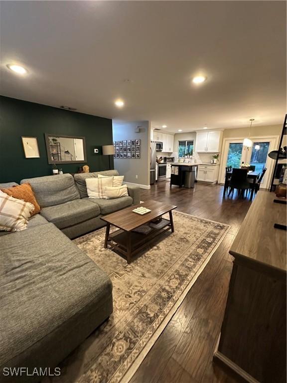 living area with dark wood-type flooring and recessed lighting