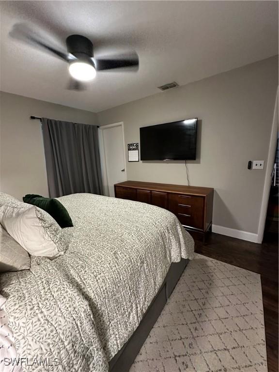 bedroom featuring dark wood-type flooring, baseboards, a ceiling fan, and visible vents