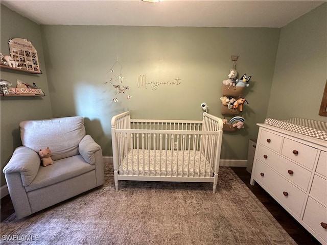 bedroom featuring a nursery area and baseboards