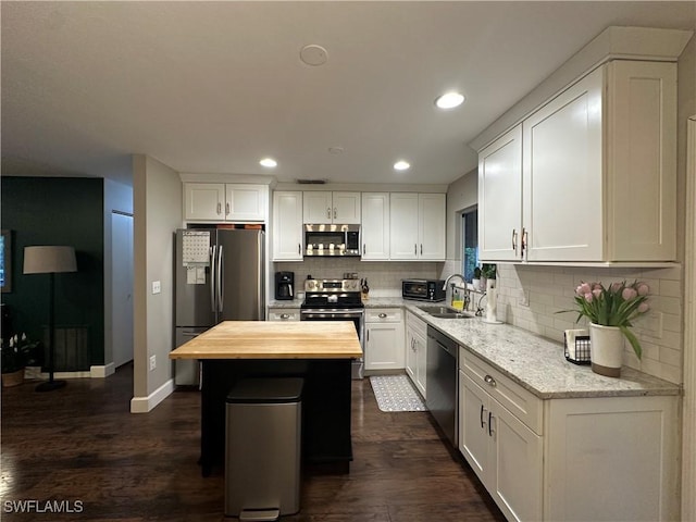 kitchen featuring tasteful backsplash, butcher block countertops, a center island, stainless steel appliances, and a sink