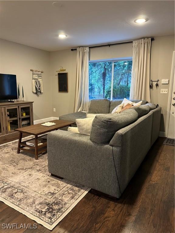 living area with dark wood-style flooring and recessed lighting