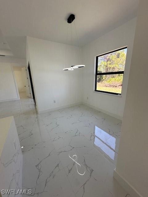 unfurnished dining area featuring baseboards and marble finish floor