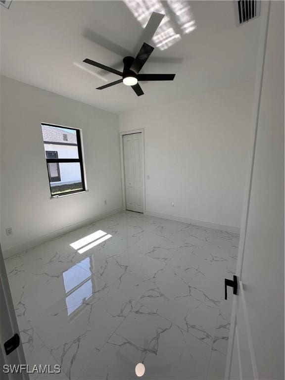 spare room with marble finish floor, baseboards, ceiling fan, and visible vents