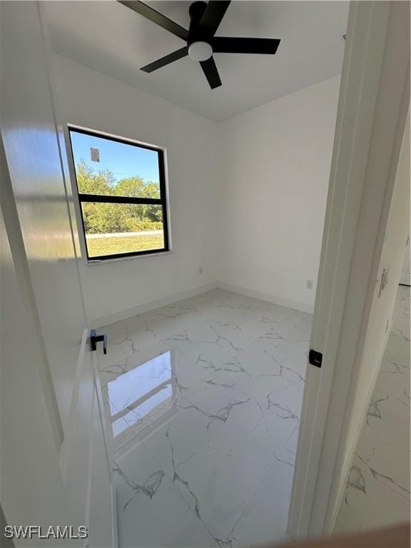 spare room featuring marble finish floor, baseboards, and a ceiling fan