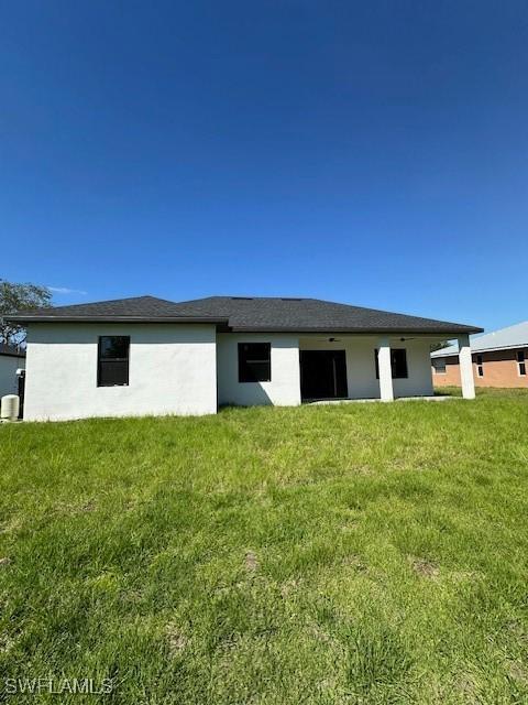 back of property featuring stucco siding and a lawn