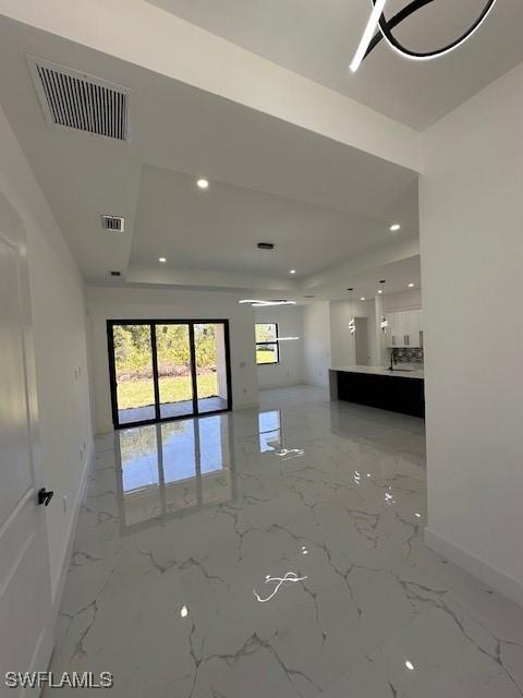 empty room with baseboards, a tray ceiling, visible vents, and recessed lighting