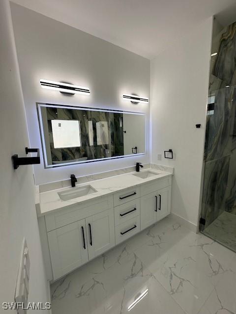 full bathroom with baseboards, a sink, a marble finish shower, and double vanity