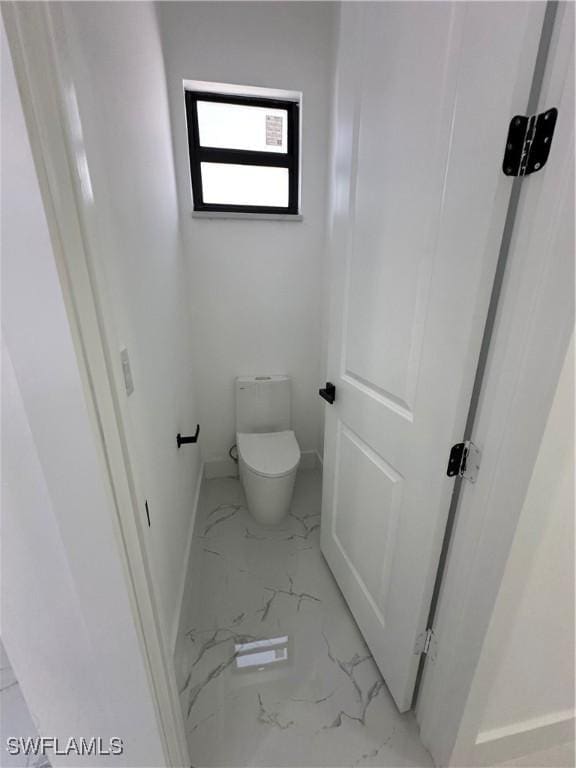 bathroom with baseboards, marble finish floor, and toilet